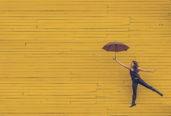 Femme prête à s'envoler à l'aide d'un parapluie